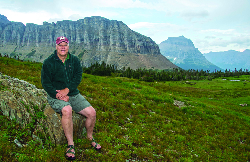 UM Professor Ric Hauer sits on a rock with special significance atop Logan Pass in Glacier National Park. It was here at the headwaters of Logan Creek where Hauer learned the U.S. Army Corps of Engineers was interested in working with him in a cooperative agreement worth $45 million.